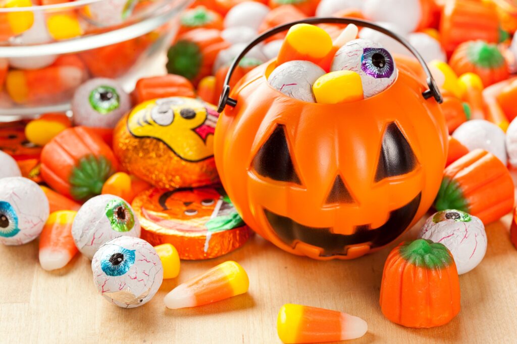 Jack-o-lantern full of candy in a pile of candy on a table